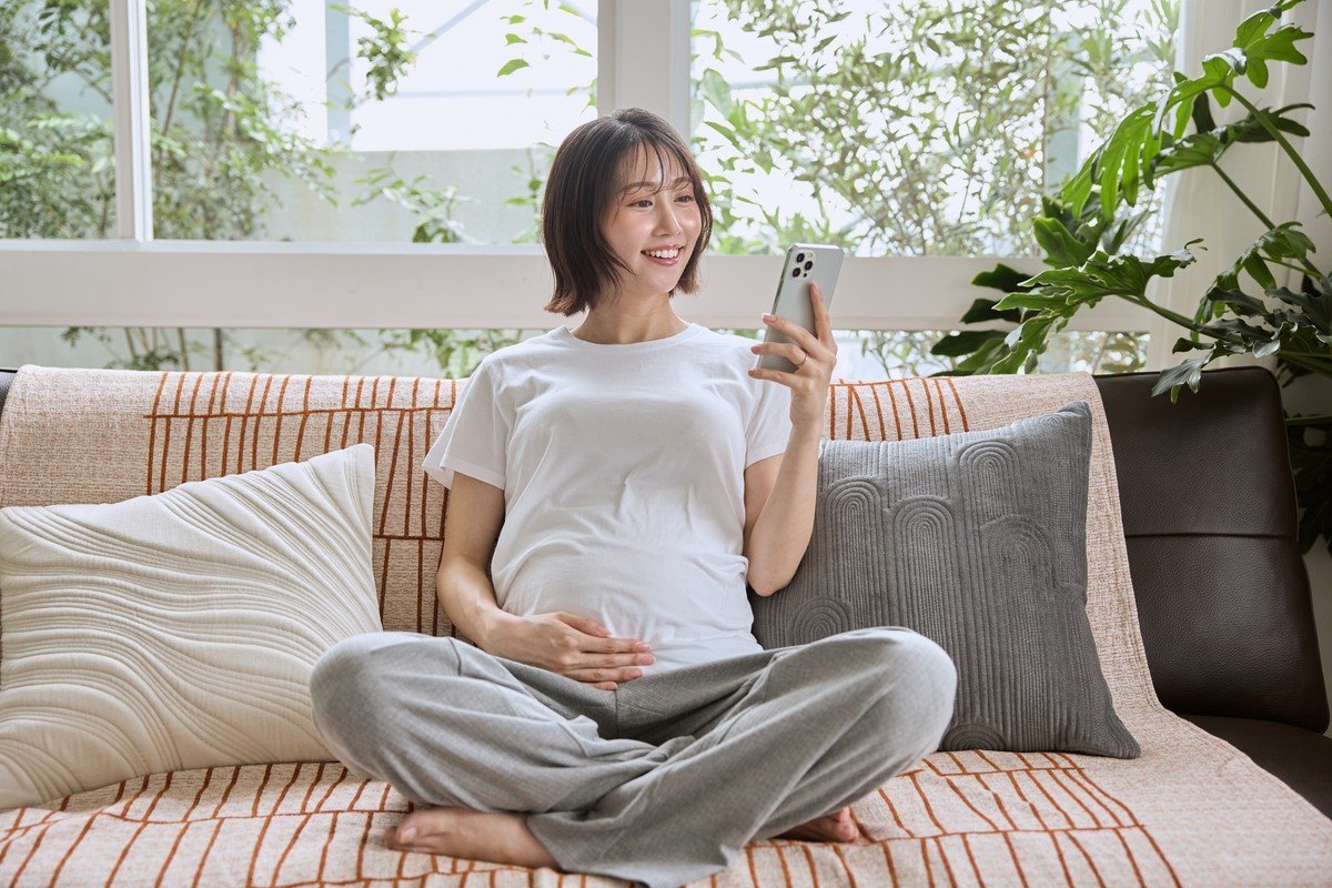 ベビーカレンダーアプリを操作するスマートフォンを持つ妊婦または母親